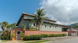 a house with a palm tree in front of it at Pousada Etoile in Juquei