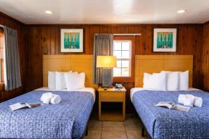 two beds in a hotel room with books on them at Sea Horse Inn and Cottages in Nags Head