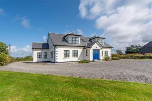 a white house with a blue door on a gravel driveway at Grianán in Ballyconneely