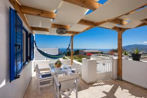 a patio with a glass table and chairs on a balcony at Anchor House Santorini in Fira