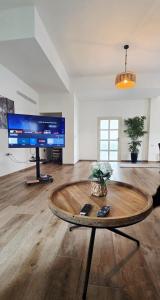a living room with a table and a large screen tv at צימר החורש in Dāliyat el Karmil