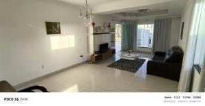 a living room with a black couch and a television at Aconchegante in São Mateus