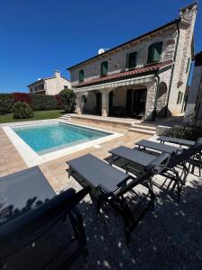a villa with a swimming pool and two picnic tables at Villa Dracena mit privatem Saltwater Pool in Višnjan