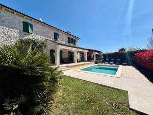 a house with a swimming pool next to a building at Villa Dracena mit privatem Saltwater Pool in Višnjan