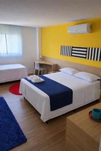 a bedroom with two beds and a yellow wall at Carambola CoLiving in Olinda