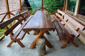 a wooden picnic table and benches on a porch at Casa Coasta Tare in Trăisteni