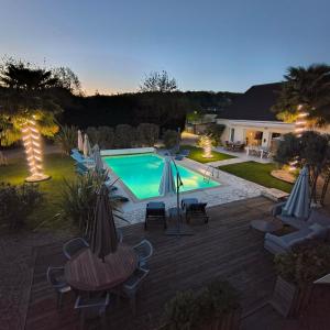 a backyard with a swimming pool and a deck with chairs and umbrellas at La Girouardière in La Flèche