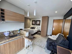 a kitchen and living room with a couch and a bed at Sun Square Suítes By Temporada Gyn in Goiânia