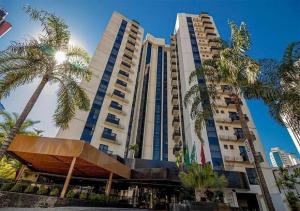 a tall building with palm trees in front of it at Sun Square Suítes By Temporada Gyn in Goiânia