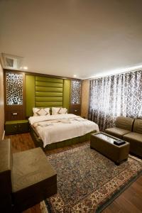 a bedroom with a large bed and a couch at Hotel Asian Comfort in Srinagar +54 photos
