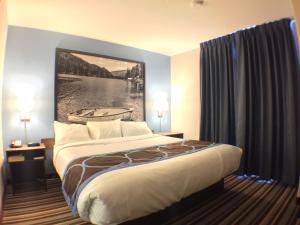 um quarto de hotel com uma cama com um quadro na parede em Super 8 by Wyndham Fort Frances em Fort Frances