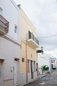 - un bâtiment blanc et jaune avec un balcon dans l'établissement La Casa di Baldo, à Ugento