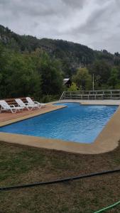 a large swimming pool with lounge chairs next to it at Turismo Shangrila - cabañas in Nevados de Chillan