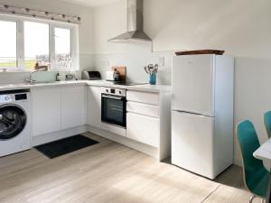 a white kitchen with a refrigerator and a dishwasher at Machermore Cottage in Gillespie