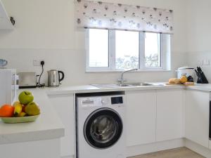 a kitchen with a washing machine and a window at Machermore Cottage in Gillespie