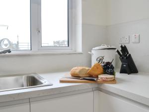 a kitchen counter with a cutting board with bread and fruit at Machermore Cottage in Gillespie