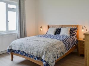 a bedroom with a bed with a blue and white comforter at Machermore Cottage in Gillespie
