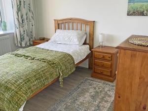 a bedroom with a bed and a wooden dresser and a night stand at Machermore Cottage in Gillespie +8 photos