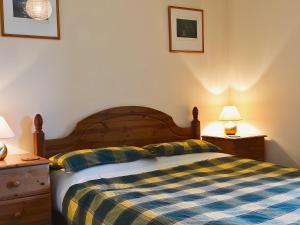 a bedroom with a bed with a plaid blanket and two lamps at Cornucopia in Portree