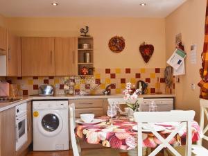 a kitchen with a table with a washing machine at Cornucopia in Portree