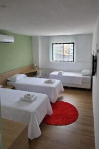 a hotel room with two beds and a red rug at Carambola CoLiving in Olinda