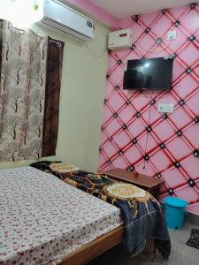a bedroom with a bed and a pink wall at Haramani Guest House in Konārka