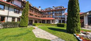 an exterior view of a large building with trees at Evelina Palace Hotel in Bansko