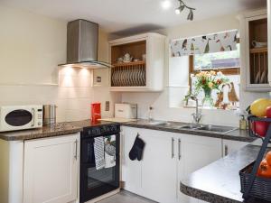 a kitchen with white cabinets and a stove top oven at Shelduck Cottage in Holmfirth