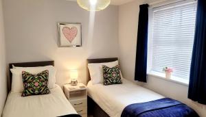 two twin beds in a room with a window at 1 Merchants Gate - 2 bedroom, city apartment with private parking in York