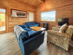 a living room with blue couches and a television at Whiteburn in Pitlochry