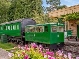 a green train parked next to a building with flowers at Sprat & Winkle in Horsebridge
