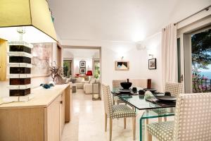 a kitchen and living room with a glass table and chairs at GOCCE VILLAS - Villa Bouganvillea Superb Capri Villa with Views in Capri +12 photos