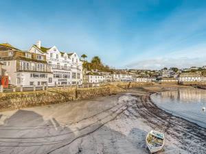 a boat on the shore of a beach with houses at The Sail Room in Saint Mawes