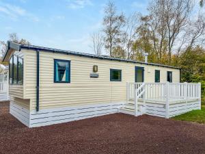 a small white house with a white fence at Eskside Lodge in Brechin