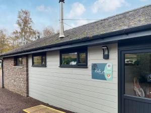 a building with a white garage door and two windows at Eskside Lodge in Brechin