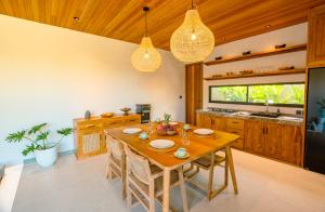 a dining room with a wooden table and a kitchen at Casa Ariana in Ubud