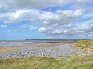 a beach with rocks and the ocean on a cloudy day at Timbers in Woolfardisworthy
