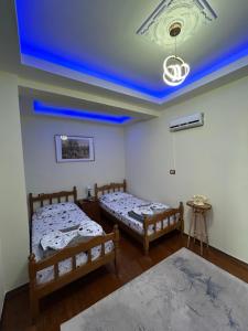 two beds in a room with a blue ceiling at Vila Spaho in Korçë