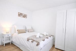 a white bedroom with a white bed with towels on it at 5 Mins to Train Station - Paris & DisneyLand - Cosy des Reves Villiers in Villiers-sur-Marne