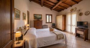 a bedroom with a white bed and a television at Casa del Borgo, between Mountains and Lake, Near Rome in Canepina
