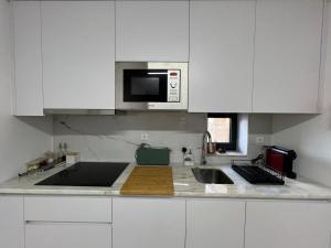 a white kitchen with a sink and a microwave at Casa das Romãs in Torre de Moncorvo