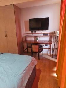 a bedroom with a bed and a desk with a flat screen tv at Galaxy Blue sapphire Plaza Square Residency in Ghaziabad +3 photos