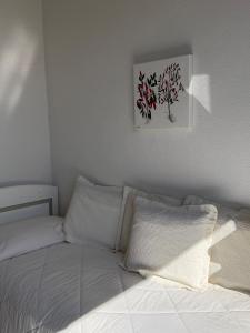 a bed with white sheets and a picture on the wall at Hotel Residence Mendolita in Lipari