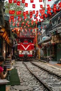 a red train on tracks in a city with flags at Maison du nook in Hanoi
