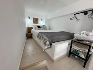 a white bedroom with a bed and a table at Babatseratsi skyrian studio 2 in Skiros