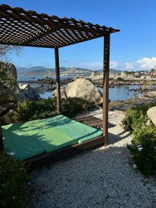 a bed under a wooden pergola next to the water at Departamentos Océano in Maitencillo +8 photos