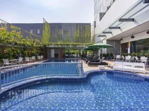 a large swimming pool with chairs and a building at ibis Styles Cikarang in Cikarang