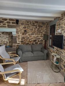 a living room with a couch and a stone wall at Les 3 Nuances in Saint-Suliac