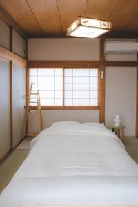 a room with a large bed and a window at ゲストハウス レトロマチカ in Sakai