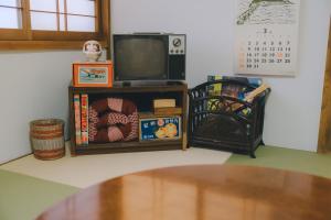 a living room with a tv and a table at ゲストハウス レトロマチカ in Sakai